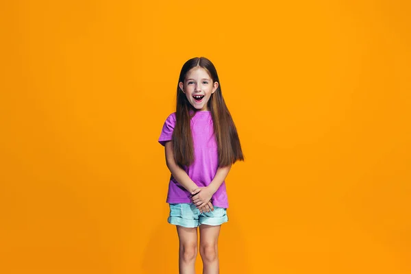 La chica adolescente feliz de pie y sonriendo contra el fondo naranja . — Foto de Stock