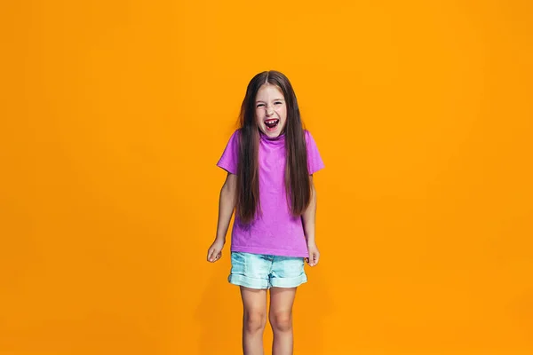 La chica adolescente feliz de pie y sonriendo contra el fondo naranja . — Foto de Stock