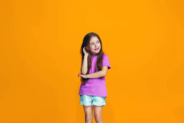 De gelukkige tiener meisje permanent en glimlachend tegen oranje achtergrond. — Stockfoto