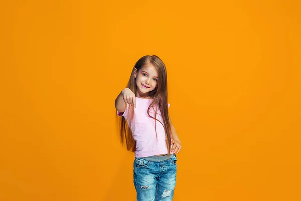 Den glada teen flicka pekar du, halv längd närbild porträtt på orange bakgrund. — Stockfoto