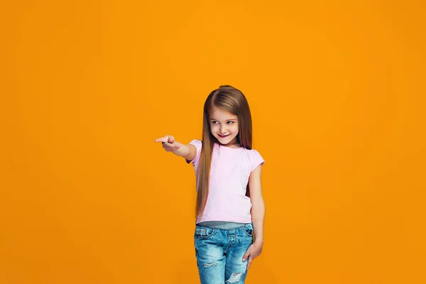 Den glada teen flicka pekar du, halv längd närbild porträtt på orange bakgrund. — Stockfoto