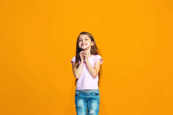 A menina adolescente feliz de pé e sorrindo contra o fundo laranja . — Fotografia de Stock