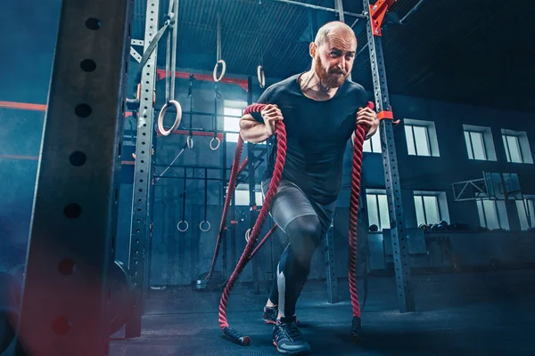 Los hombres con cuerdas de batalla se ejercitan en el gimnasio. CrossFit . —  Fotos de Stock