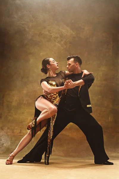 Dance ballroom casal em vestido de ouro dançando no fundo do estúdio . — Fotografia de Stock