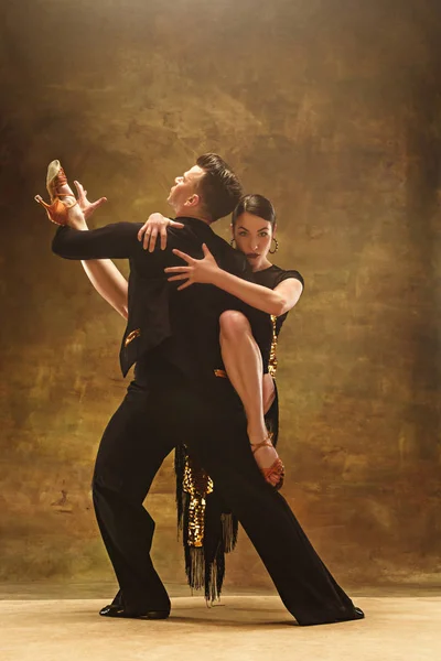 Tańca towarzyskiego para w złota sukienka taniec na tle studio. — Zdjęcie stockowe
