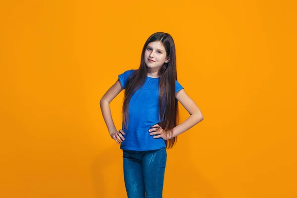 立っていると、オレンジ色の背景に対して笑顔幸せな十代の少女. — ストック写真