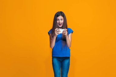 Mutlu genç kız ayakta ve turuncu arka planı gülümseyen.