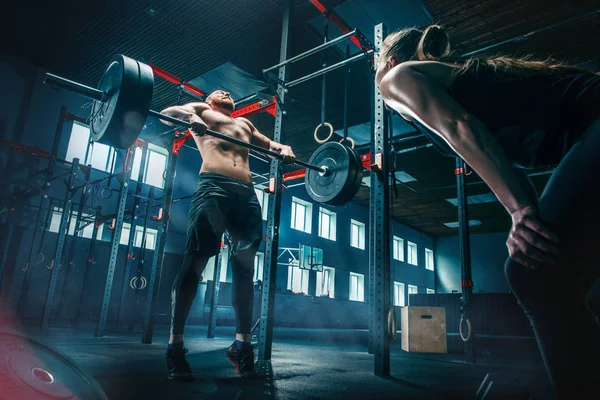 Ajuste joven levantando barras de entrenamiento en un gimnasio — Foto de Stock