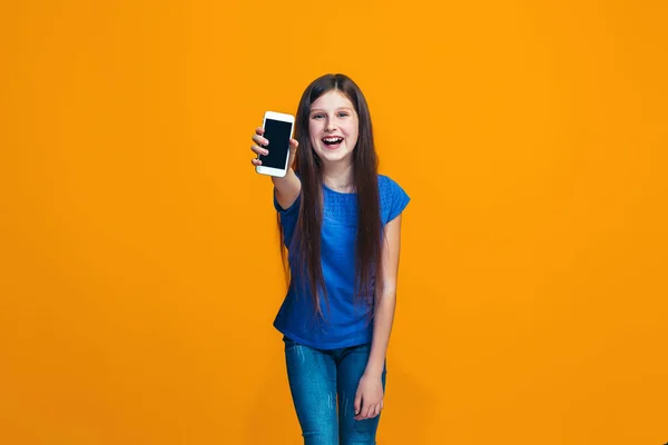 La chica adolescente feliz de pie y sonriendo contra el fondo naranja . —  Fotos de Stock