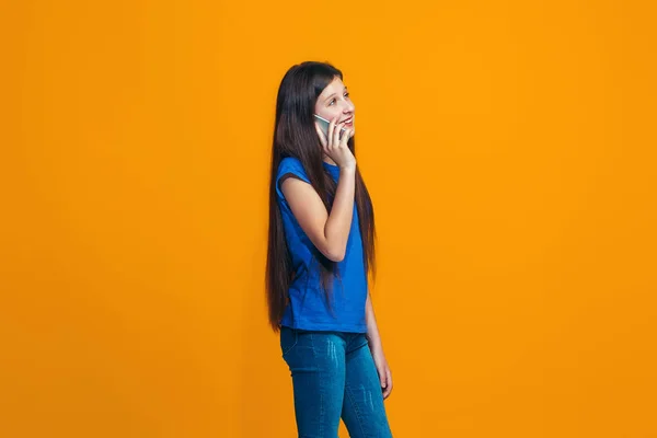 L'adolescente heureuse debout et souriante sur fond orange . — Photo