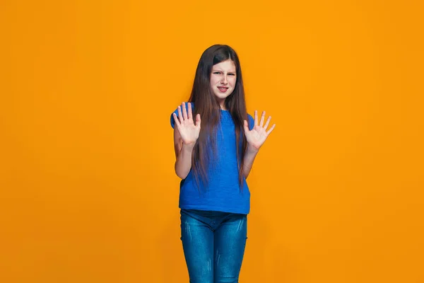 Dudosa chica adolescente pensativa rechazando algo contra fondo naranja — Foto de Stock