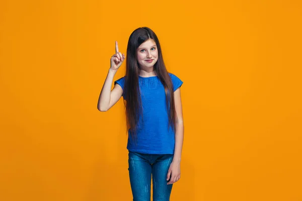 Щаслива дівчина-підліток стоїть і посміхається на помаранчевому фоні . — стокове фото