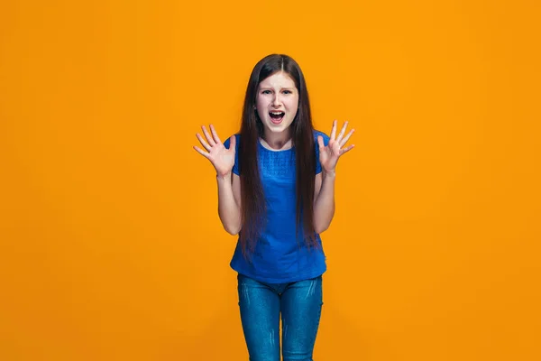 Портрет злой девочки-подростка на фоне оранжевой студии — стоковое фото