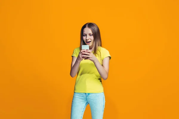 La chica adolescente feliz de pie y sonriendo contra el fondo naranja . — Foto de Stock