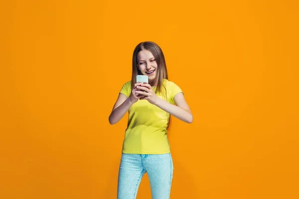 La chica adolescente feliz de pie y sonriendo contra el fondo naranja . —  Fotos de Stock