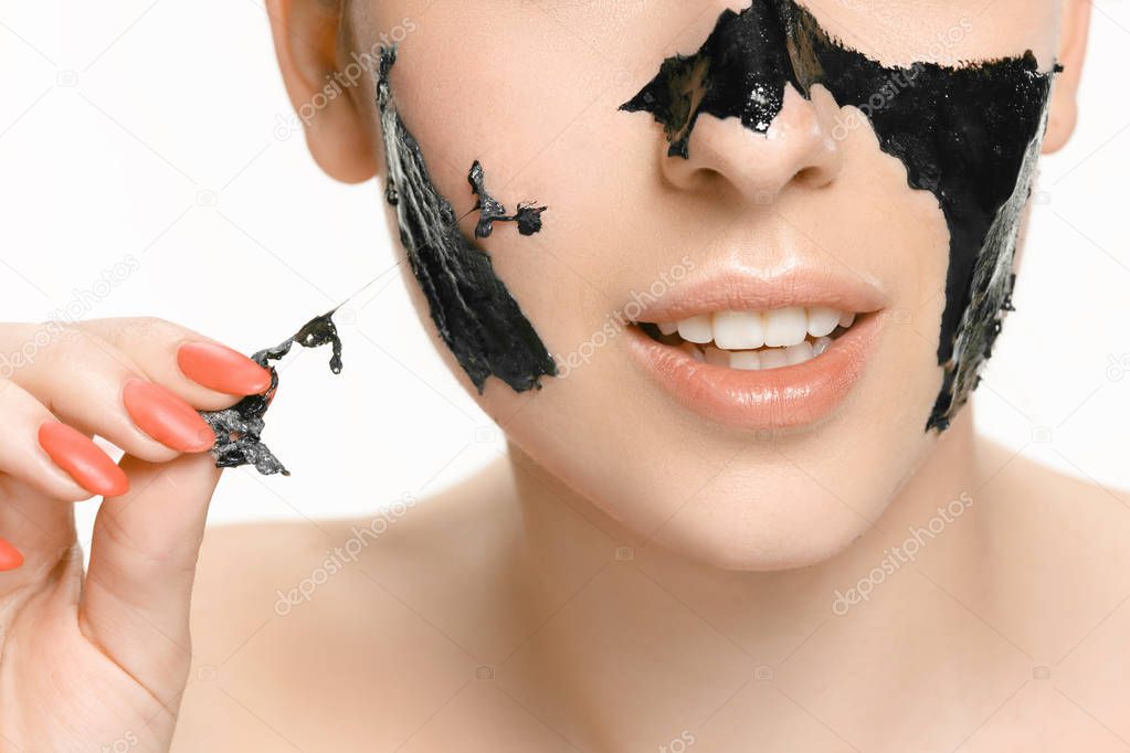 Young beautiful woman applying a mask for the face of the therapeutic black mud. Spa treatment