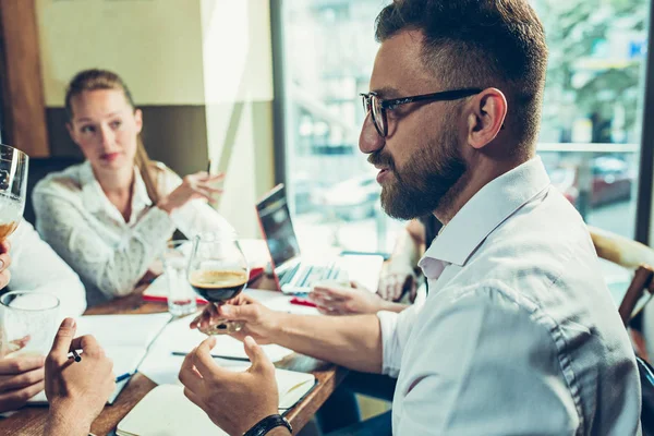 Los jóvenes alegres sonríen y hacen gestos mientras se relajan en el pub . — Foto de Stock