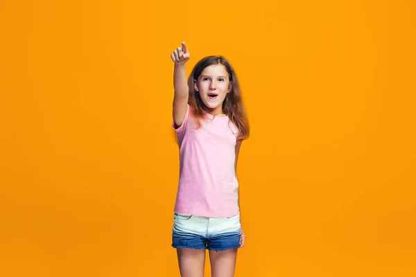 Den glada teen flicka pekar du, halv längd närbild porträtt på orange bakgrund. — Stockfoto