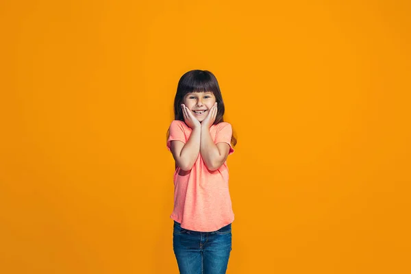 L'adolescente heureuse debout et souriante sur fond orange . — Photo