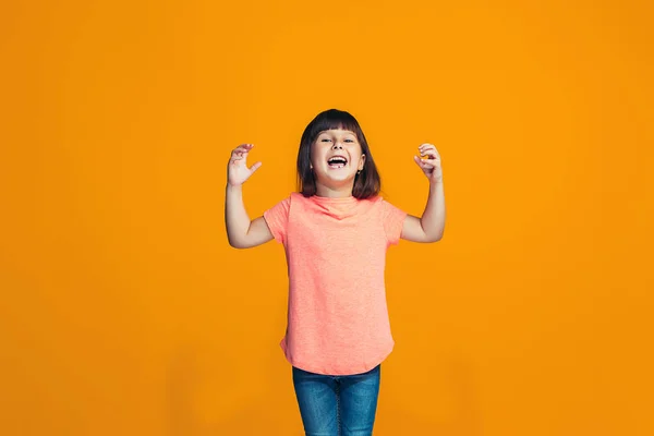 Šťastný dospívající dívka stojící a usmívá se proti oranžové pozadí. — Stock fotografie