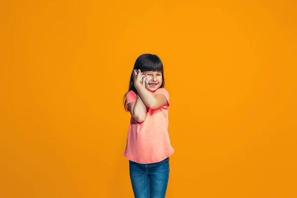 Ευτυχής έφηβος κορίτσι στέκεται και χαμογελαστός σε πορτοκαλί φόντο. — Φωτογραφία Αρχείου