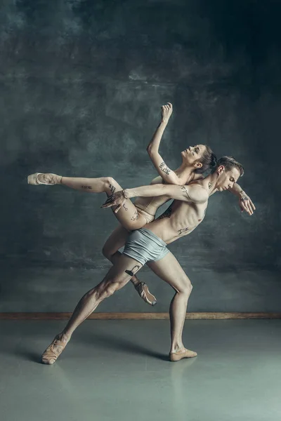 De jonge moderne balletdansers poseren op grijze studio achtergrond — Stockfoto