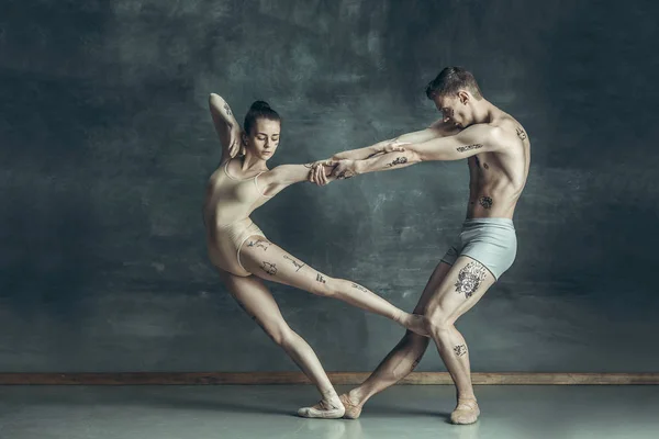 Os jovens bailarinos modernos posando no fundo do estúdio cinza — Fotografia de Stock