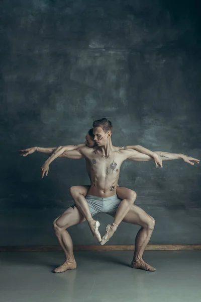 Молодые современные артисты балета позируют на фоне серой студии — стоковое фото