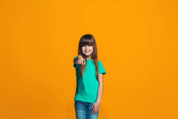 Счастливая девочка-подросток, указывающая на тебя, портрет крупным планом на оранжевом фоне . — стоковое фото