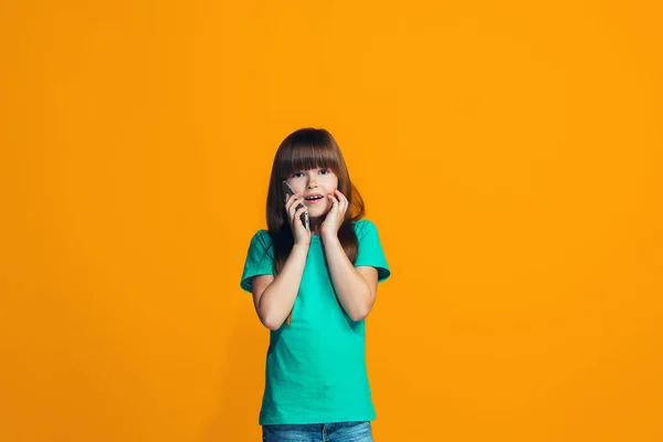 Gadis remaja yang bahagia berdiri dan tersenyum dengan latar belakang oranye . — Stok Foto