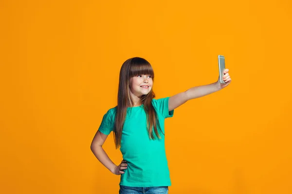 La chica adolescente feliz de pie y sonriendo contra el fondo naranja . —  Fotos de Stock