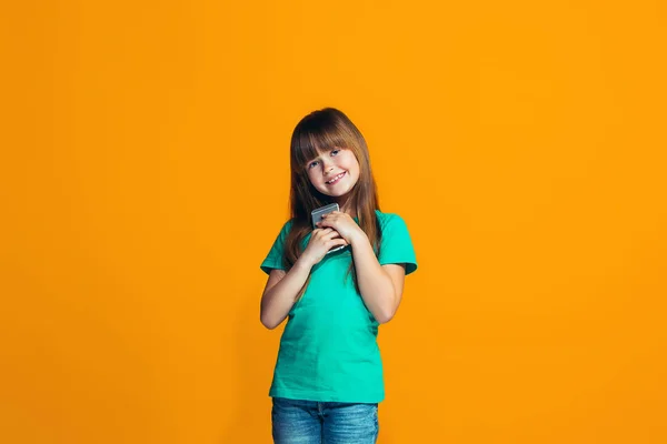 Счастливая девушка-подросток, стоящая и улыбающаяся на оранжевом фоне . — стоковое фото