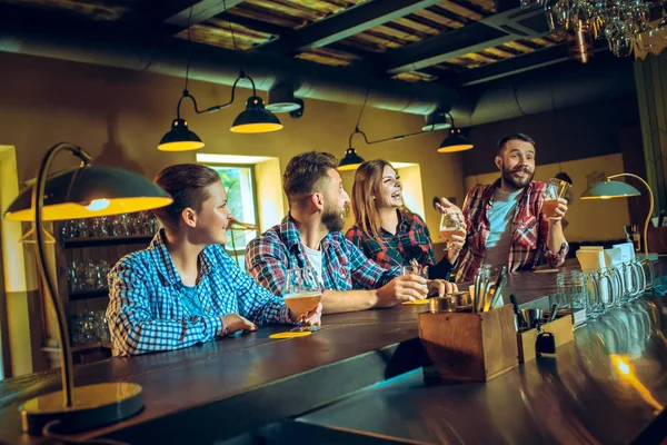 Sport, people, leisure, friendship and entertainment concept - happy football fans or male friends drinking beer and celebrating victory at bar or pub