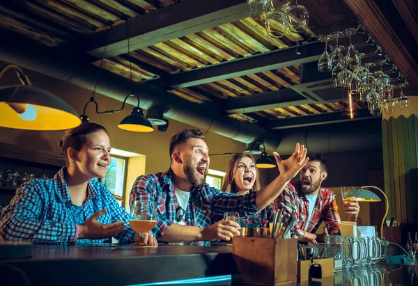 Sport, people, leisure, friendship and entertainment concept - happy football fans or male friends drinking beer and celebrating victory at bar or pub