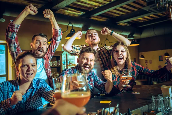 Sport, people, leisure, friendship and entertainment concept - happy football fans or male friends drinking beer and celebrating victory at bar or pub