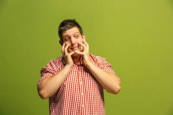 Hermoso hombre mirando sorprendido y desconcertado aislado en verde — Foto de Stock