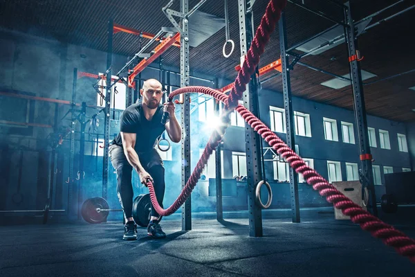 Los hombres con cuerdas de batalla se ejercitan en el gimnasio de fitness . —  Fotos de Stock