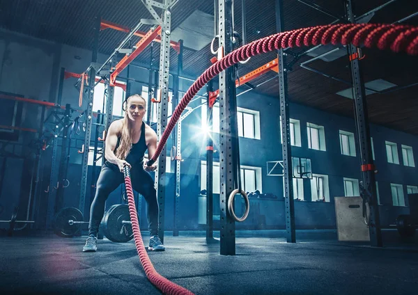 Mujer con cuerdas de batalla Las cuerdas de batalla se ejercitan en el gimnasio . — Foto de Stock