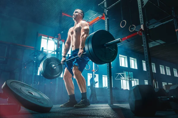 Ajuste joven levantando barras de entrenamiento en un gimnasio — Foto de Stock