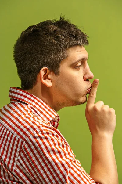 El joven susurrando un secreto detrás de su mano sobre el fondo verde —  Fotos de Stock