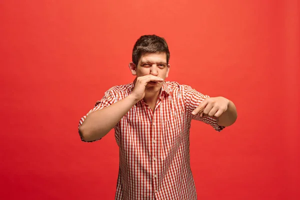 El joven susurrando un secreto detrás de su mano sobre el fondo rojo — Foto de Stock