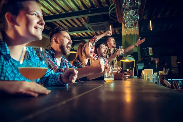 Sport, people, leisure, friendship and entertainment concept - happy football fans or male friends drinking beer and celebrating victory at bar or pub