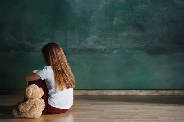 Menina com ursinho sentado no chão em quarto vazio. Conceito de autismo — Fotografia de Stock