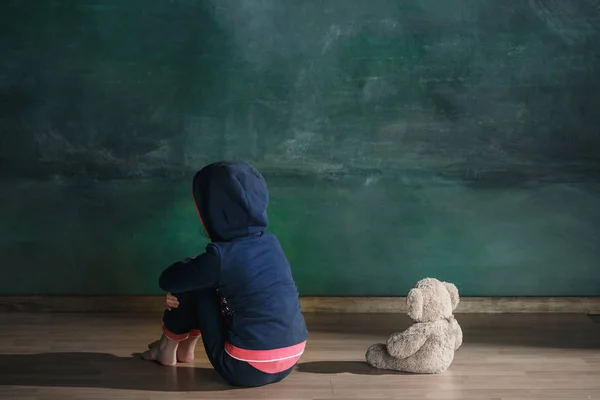 Menina com ursinho sentado no chão em quarto vazio. Conceito de autismo — Fotografia de Stock