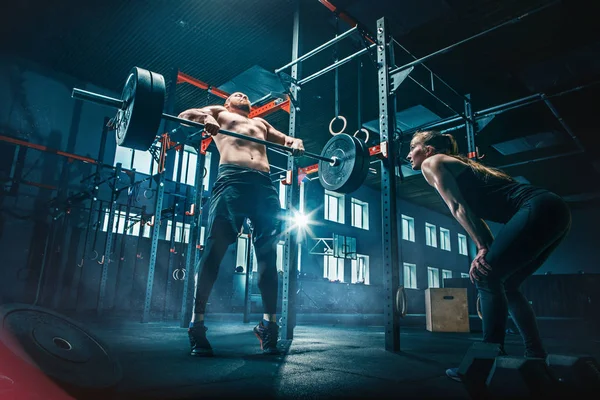 Ajuste joven levantando barras de entrenamiento en un gimnasio — Foto de Stock