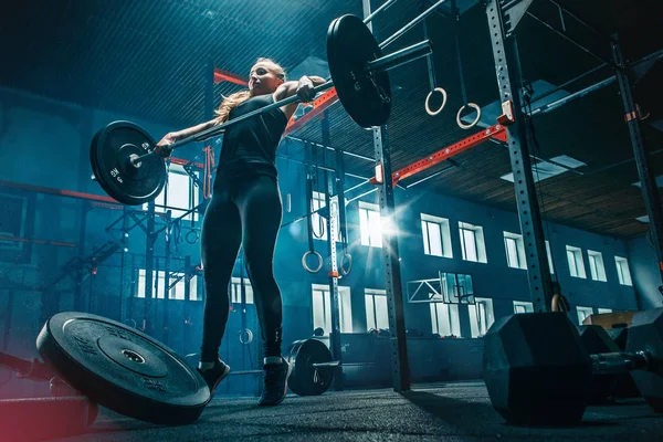 Ajuste mujer joven levantando barras de ejercicio en un gimnasio — Foto de Stock