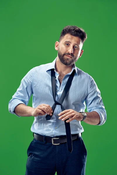 Empresário amarrando sua gravata no estúdio verde — Fotografia de Stock
