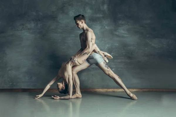 Moderní mladé baletky pózuje na šedé studio pozadí — Stock fotografie