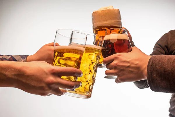 Händer med muggar öl rostningen skapa splash isolerad på vit bakgrund — Stockfoto