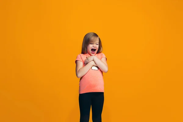 Den glada teen flicka står och ler mot orange bakgrund. — Stockfoto